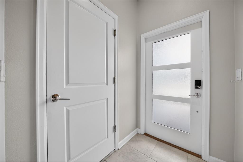 An entryway features a white paneled door, a modern door with frosted glass, and tile flooring — 1181 DROP LANE UNIT 0, DAVENPORT, FL
