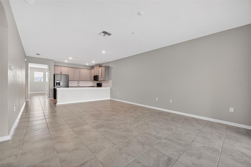 An open-concept kitchen and living area with tile flooring and light gray walls — 1181 DROP LANE UNIT 0, DAVENPORT, FL