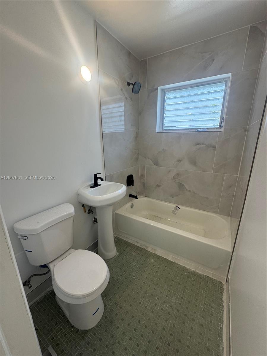 A bathroom features a pedestal sink, a toilet, and a bathtub with tiled walls — 7300 Harding Ave # 21, Miami Beach FL 33141, MIAMI BEACH, FL