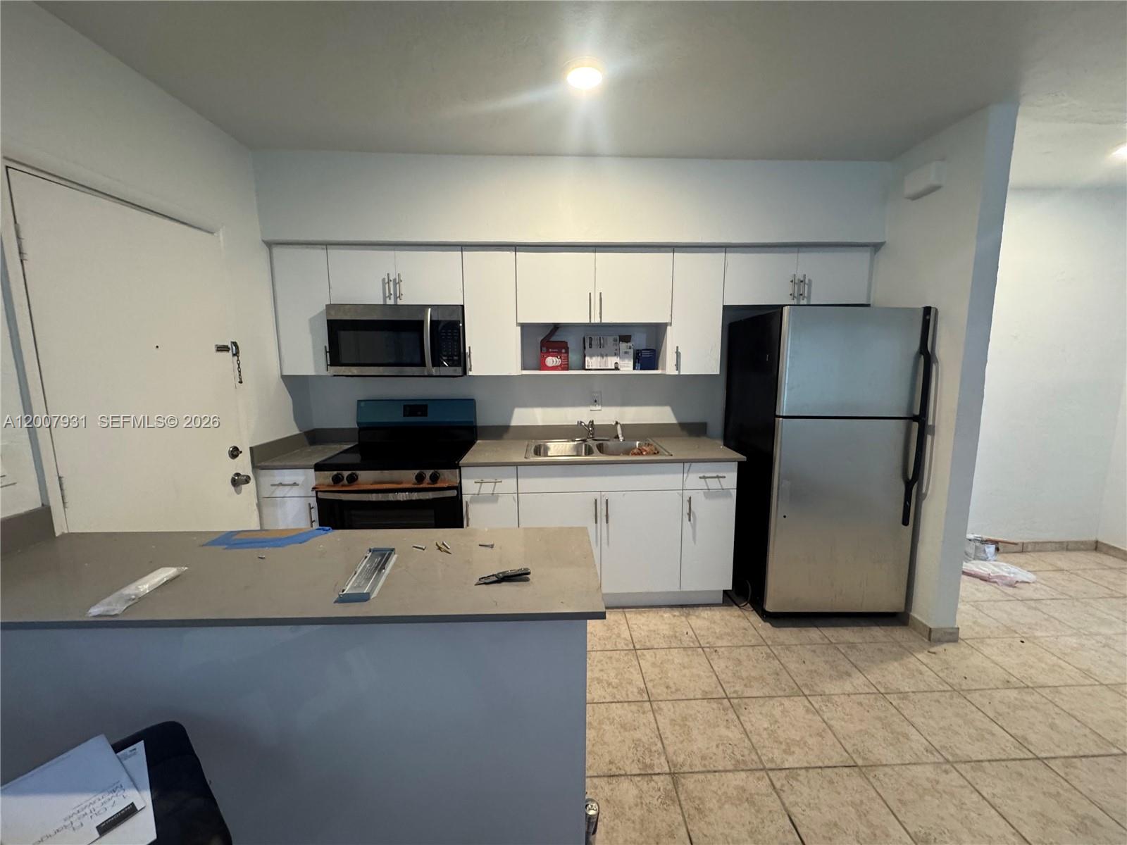 A kitchen features white cabinetry, stainless steel appliances, and a gray countertop peninsula — 7300 Harding Ave # 21, Miami Beach FL 33141, MIAMI BEACH, FL