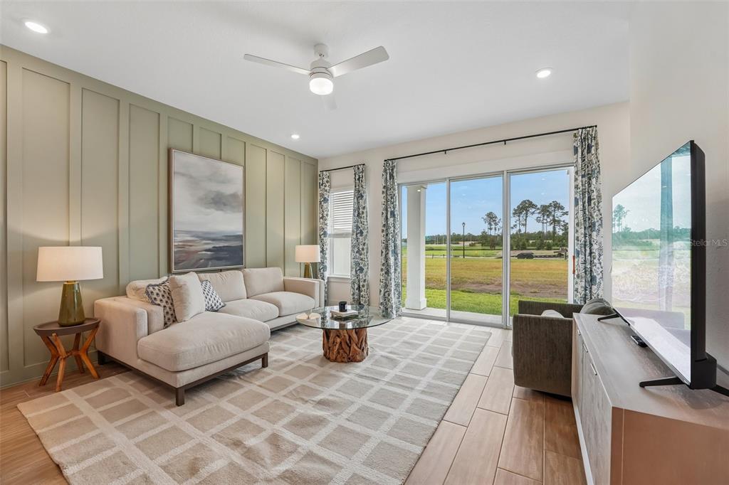 A living room features a green paneled accent wall, a sectional sofa, and sliding glass doors — 15010 CATTERICK COURT, JACKSONVILLE, FL