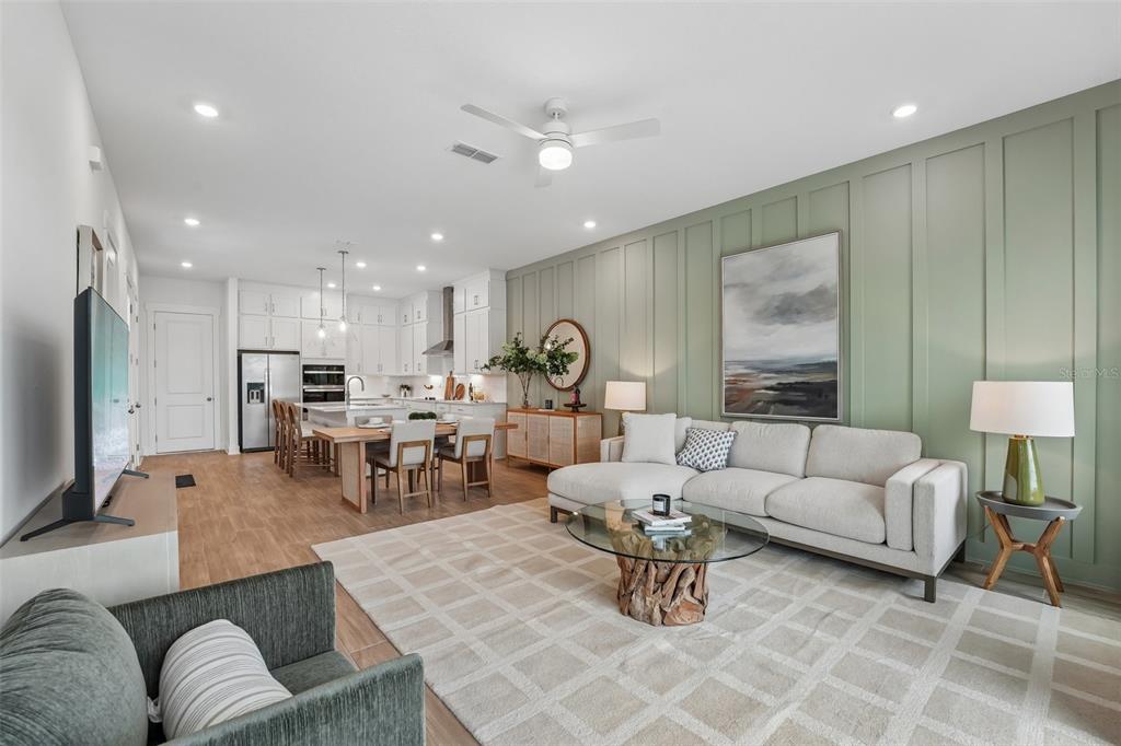 An open-concept living room and kitchen featuring a green paneled wall and neutral furniture — 15010 CATTERICK COURT, JACKSONVILLE, FL