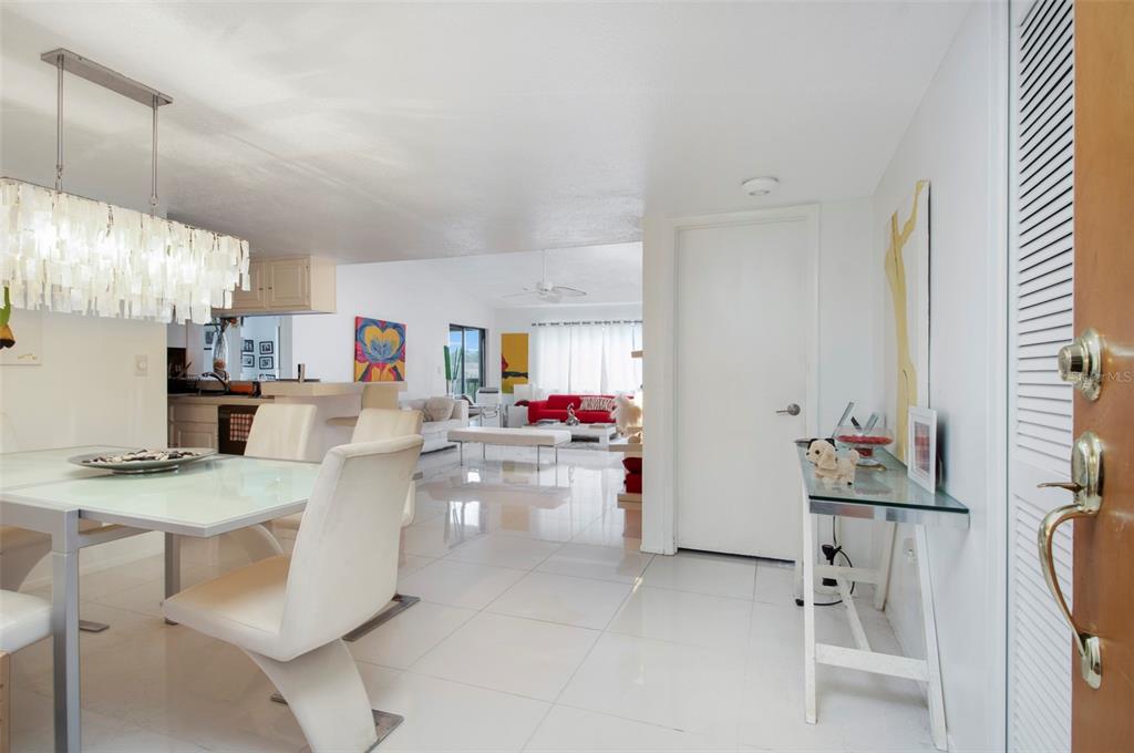 A bright, open-concept living and dining area features white tile floors and modern furniture — 2593 COUNTRYSIDE BOULEVARD UNIT 7313, CLEARWATER, FL