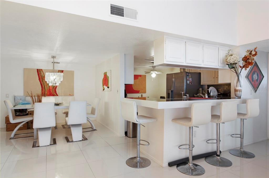 A dining area and kitchen breakfast bar with white chairs and tile flooring — 2593 COUNTRYSIDE BOULEVARD UNIT 7313, CLEARWATER, FL