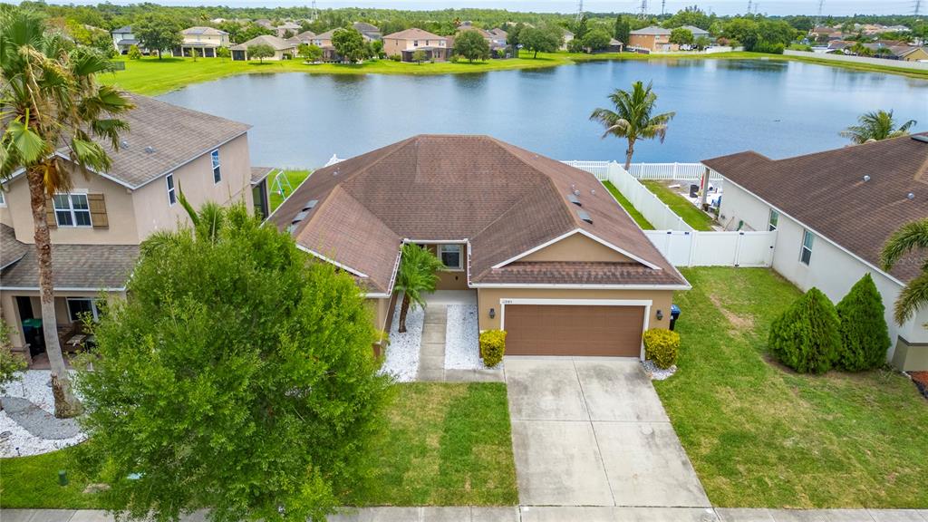 An aerial view shows a single-story house with a brown roof, garage, and backyard lake — 12845 SAWGRASS PINE CIRCLE, ORLANDO, FL