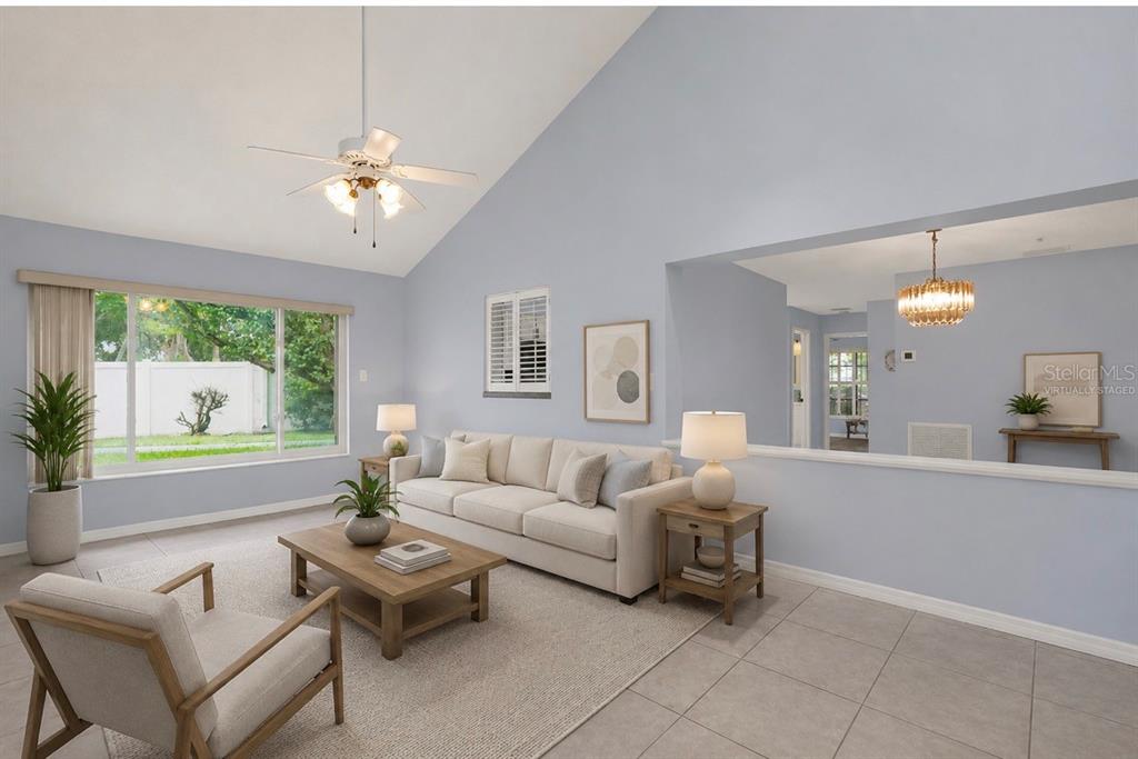 A living room with vaulted ceilings, tile floors, and a large window, featuring virtual staging — 2807 SUNBRANCH DRIVE, ORLANDO, FL