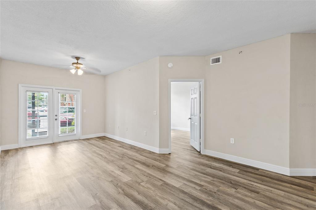A living room with light-colored walls, wood-look flooring, a ceiling fan, and glass patio doors — 10855 WINDSOR WALK DRIVE UNIT 5107, ORLANDO, FL