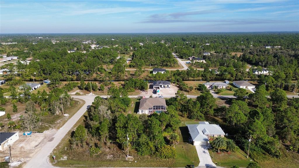 An aerial view shows several houses surrounded by dense trees and a canal — 1015 CRESTHAVEN STREET, LEHIGH ACRES, FL