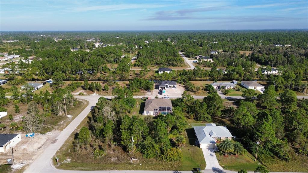 An aerial view shows several houses surrounded by dense trees and undeveloped land — 1015 CRESTHAVEN STREET, LEHIGH ACRES, FL