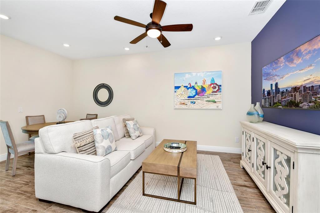A living room with a white sofa, wooden coffee table, and a wall-mounted television — 3113 CARIBBEAN SOUL DRIVE, KISSIMMEE, FL