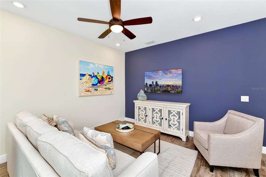 A living room features a blue accent wall, a television, a sofa, and an armchair — 3113 CARIBBEAN SOUL DRIVE, KISSIMMEE, FL