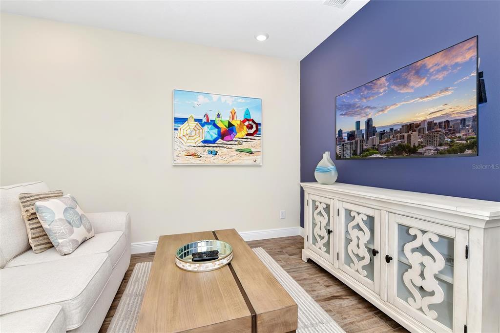 A living room features a white sofa, a wooden coffee table, and a blue accent wall — 3113 CARIBBEAN SOUL DRIVE, KISSIMMEE, FL