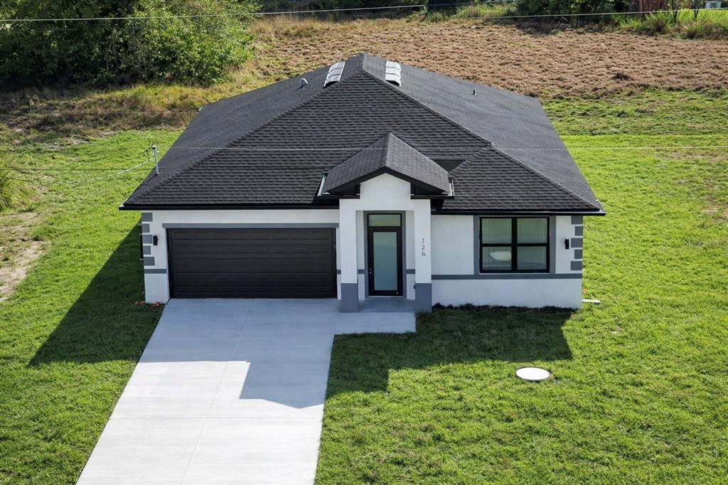 An aerial view of a single-story house with a dark roof, white stucco, and driveway — 336 SUNSET ROAD, ROTONDA WEST, FL