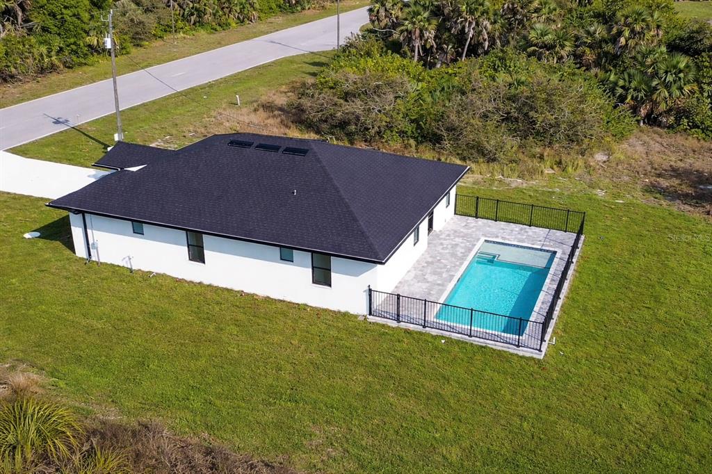 An aerial view shows a white house with a black roof, pool, and fenced patio — 336 SUNSET ROAD, ROTONDA WEST, FL