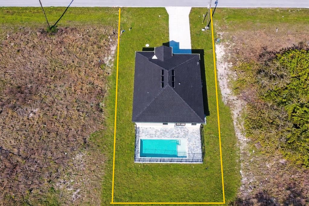 An aerial view shows a house with a pool and a fenced yard on a lot — 336 SUNSET ROAD, ROTONDA WEST, FL