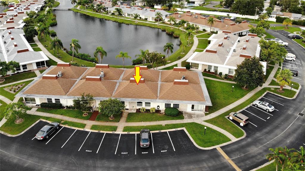 An aerial view shows a multi-unit residential building with brown roofs near a pond — 4334 TAHITIAN GARDENS CIRCLE UNIT C, HOLIDAY, FL