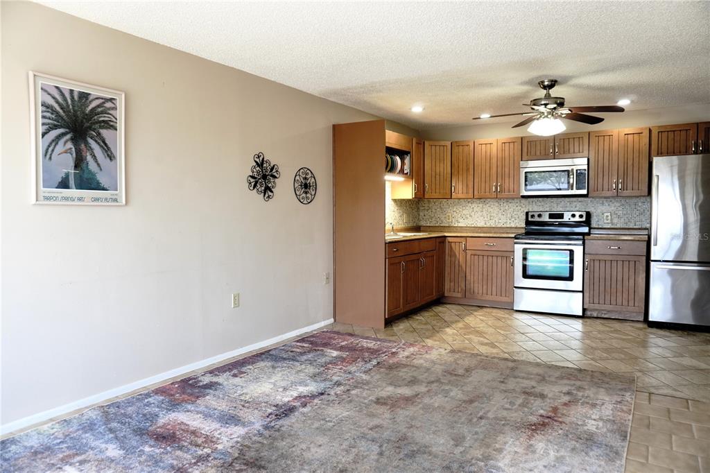 A kitchen with wood cabinets and stainless steel appliances sits adjacent to a dining area — 4334 TAHITIAN GARDENS CIRCLE UNIT C, HOLIDAY, FL