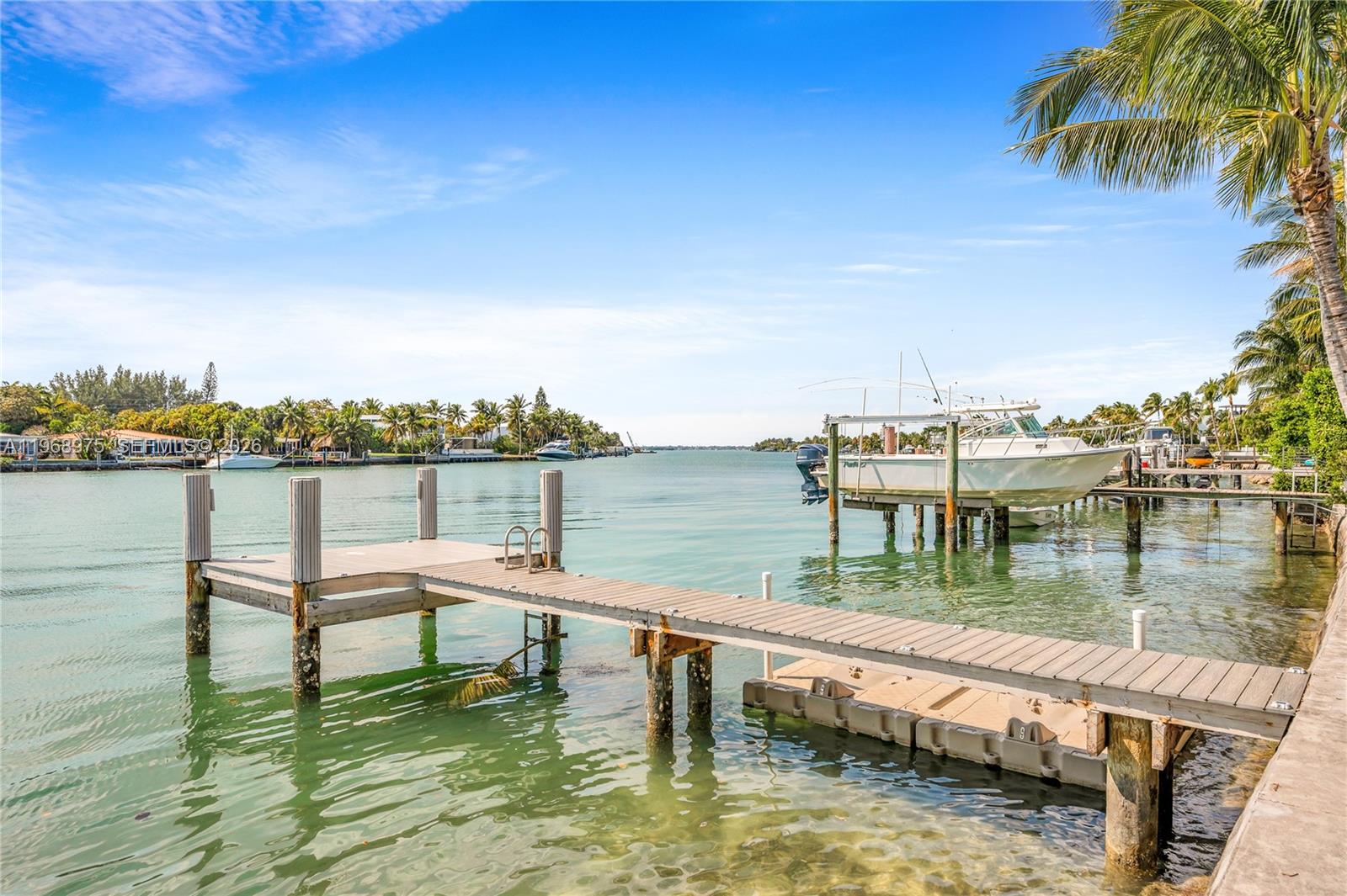 A wooden dock extends into a calm canal with a boat moored nearby — 1170 S Biscayne Point Rd, Miami Beach FL 33141, MIAMI BEACH, FL