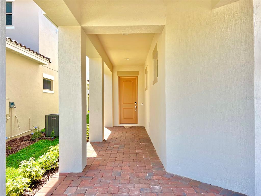 A covered entryway features a brick paver floor leading to a tan front door — 13136 WEAVER AVENUE, ORLANDO, FL