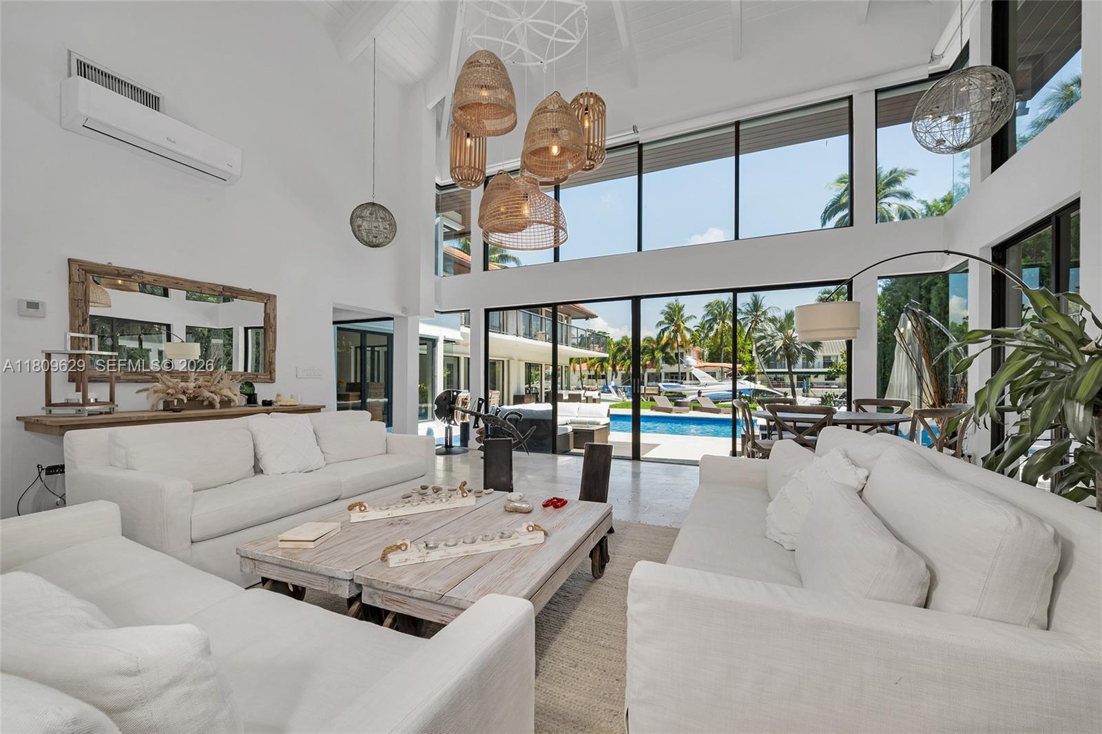 A bright, high-ceilinged living room features white sofas, a wooden coffee table, and large windows — 201 Knollwood Dr, Key Biscayne FL 33149, KEY BISCAYNE, FL