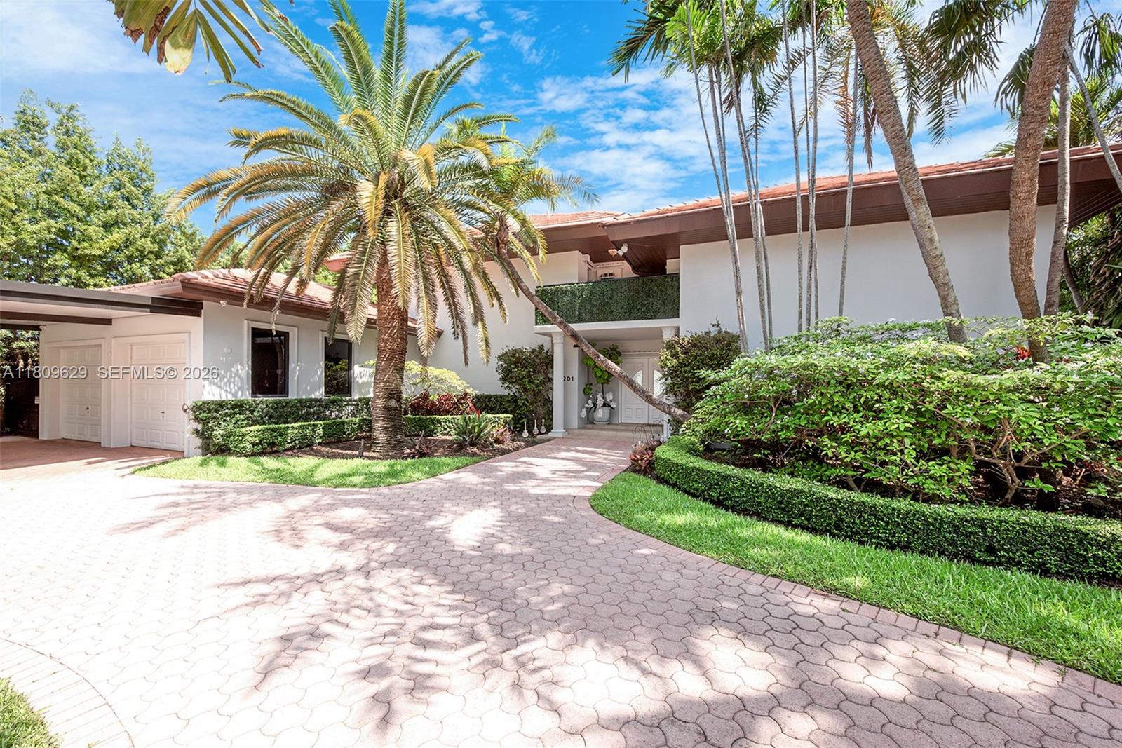 A two-story house features a paved driveway, palm trees, and manicured landscaping — 201 Knollwood Dr, Key Biscayne FL 33149, KEY BISCAYNE, FL