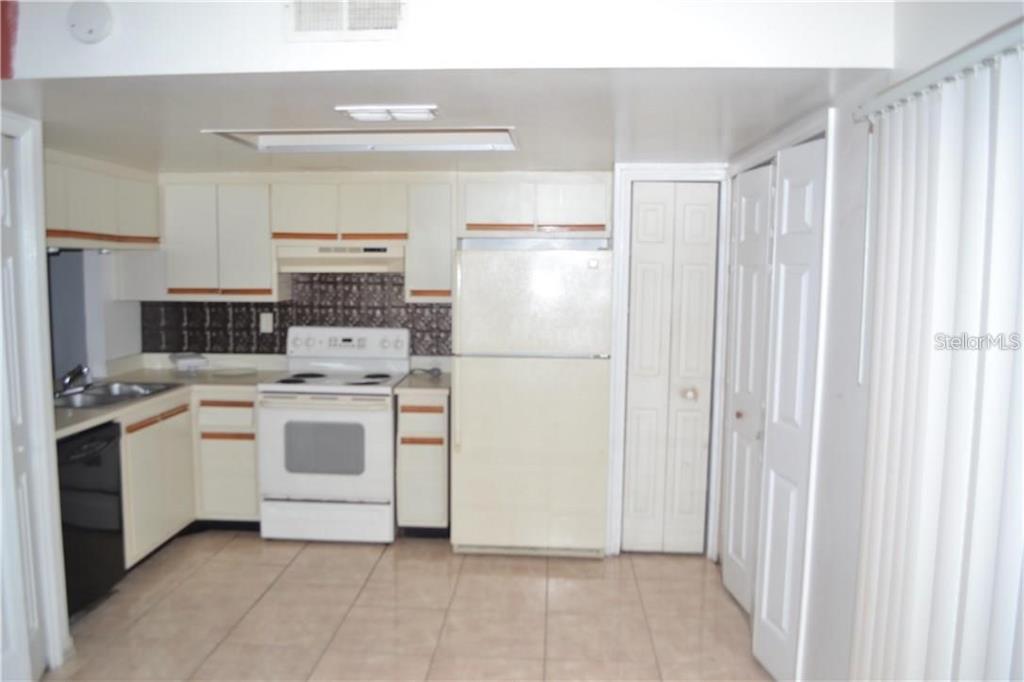 A kitchen with white cabinets, a white stove, a refrigerator, and tiled flooring — 3214 RIO GRANDE TRL UNIT 00, KISSIMMEE, FL