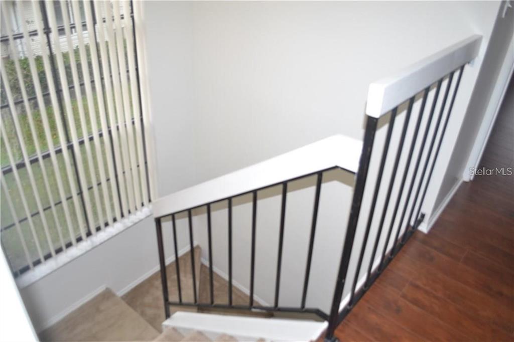 A staircase with carpeted steps and a black metal railing leads down to a window — 3214 RIO GRANDE TRL UNIT 00, KISSIMMEE, FL
