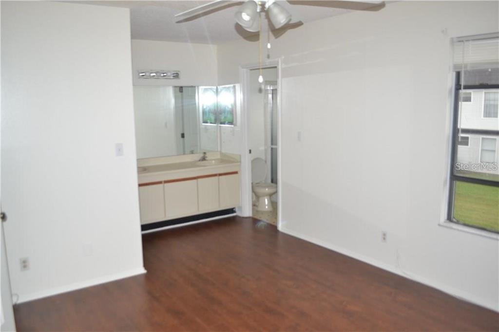 A bedroom with dark wood-look flooring, a vanity area, and an attached bathroom — 3214 RIO GRANDE TRL UNIT 00, KISSIMMEE, FL