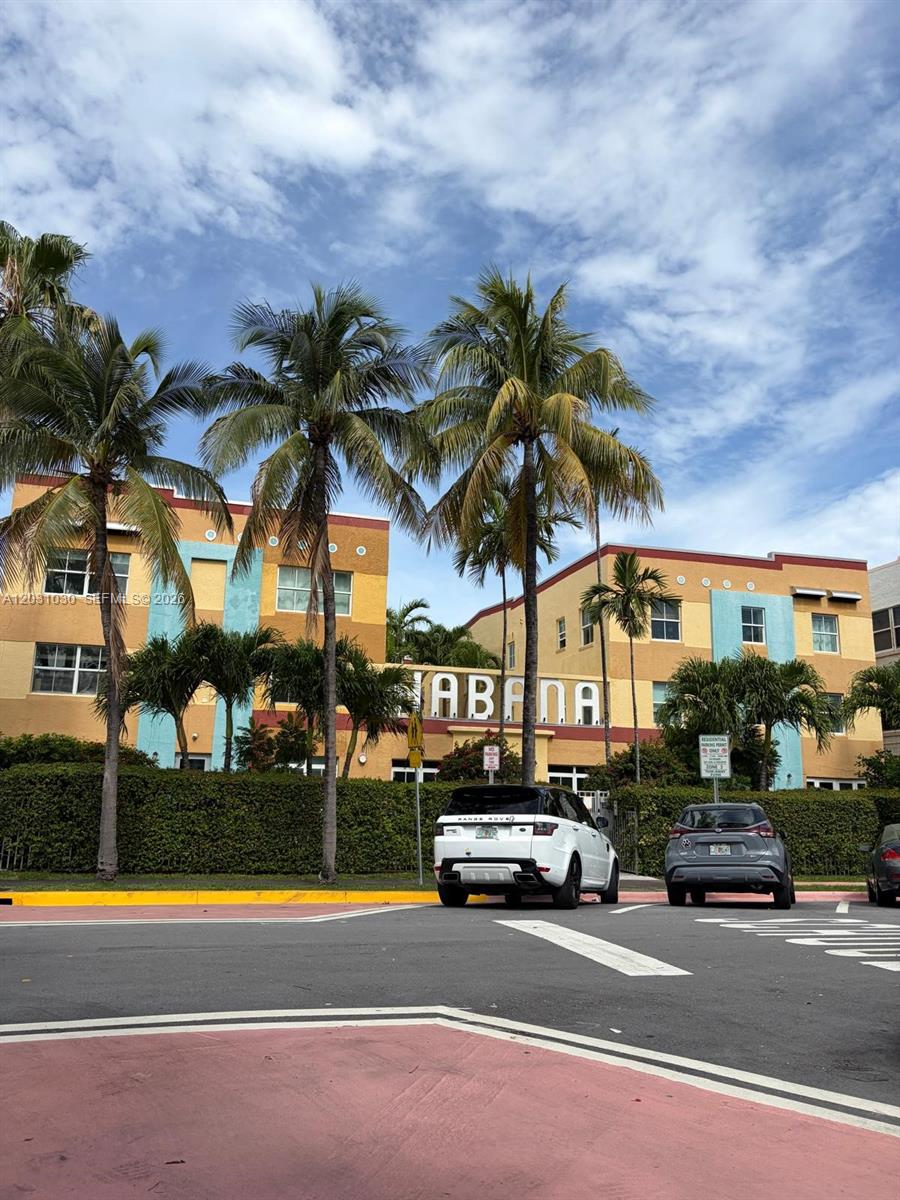 A multi-story apartment building with yellow and blue exterior walls stands behind palm trees — 1308 Drexel Ave # 311, Miami Beach FL 33139, MIAMI BEACH, FL