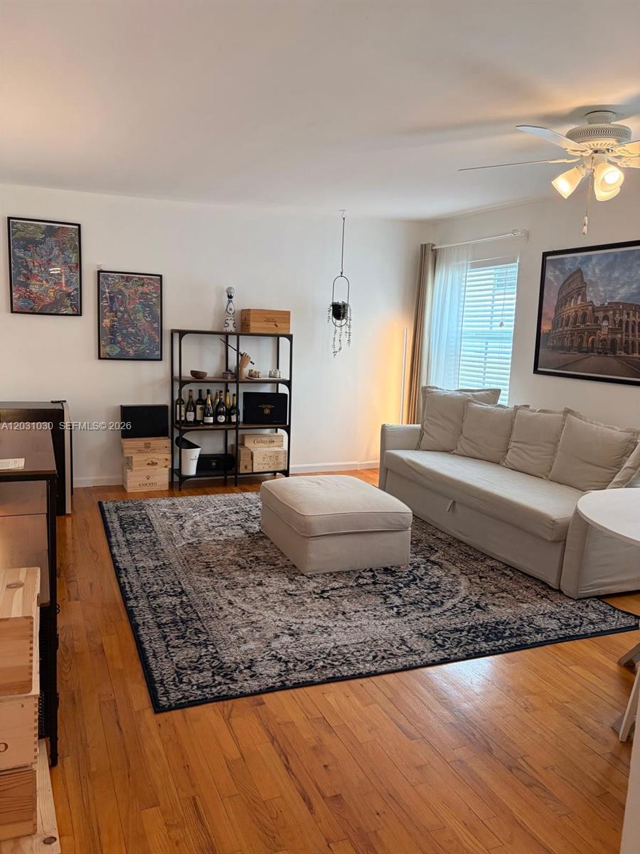 A living room features a beige sofa, matching ottoman, area rug, and wooden flooring — 1308 Drexel Ave # 311, Miami Beach FL 33139, MIAMI BEACH, FL