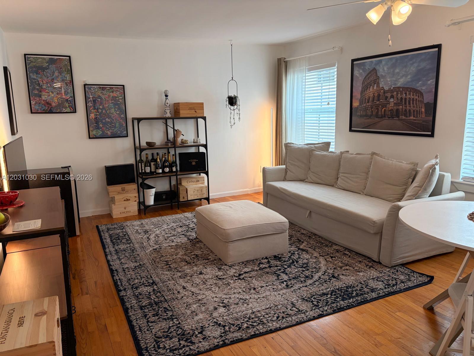 A living room features a beige sofa, a matching ottoman, and a dark patterned rug — 1308 Drexel Ave # 311, Miami Beach FL 33139, MIAMI BEACH, FL