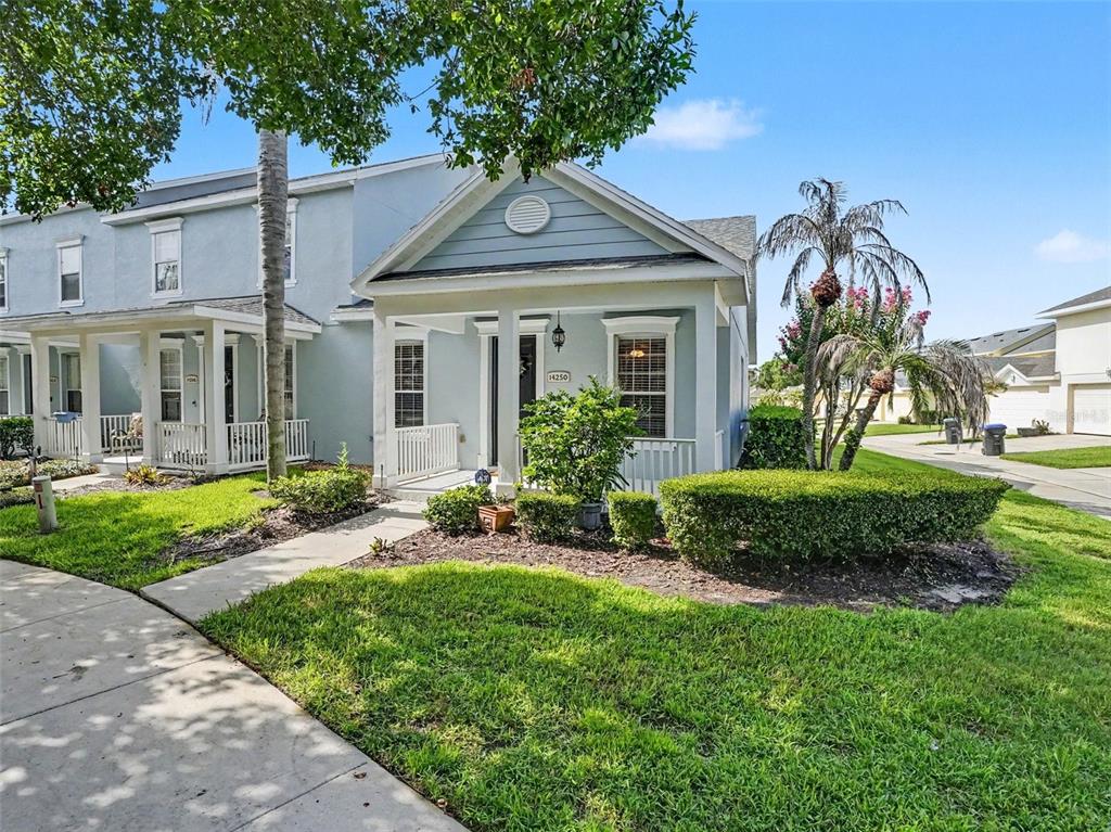 A light blue townhouse with a front porch, white railings, and a landscaped front yard — 14250 SONCO, WINDERMERE, FL