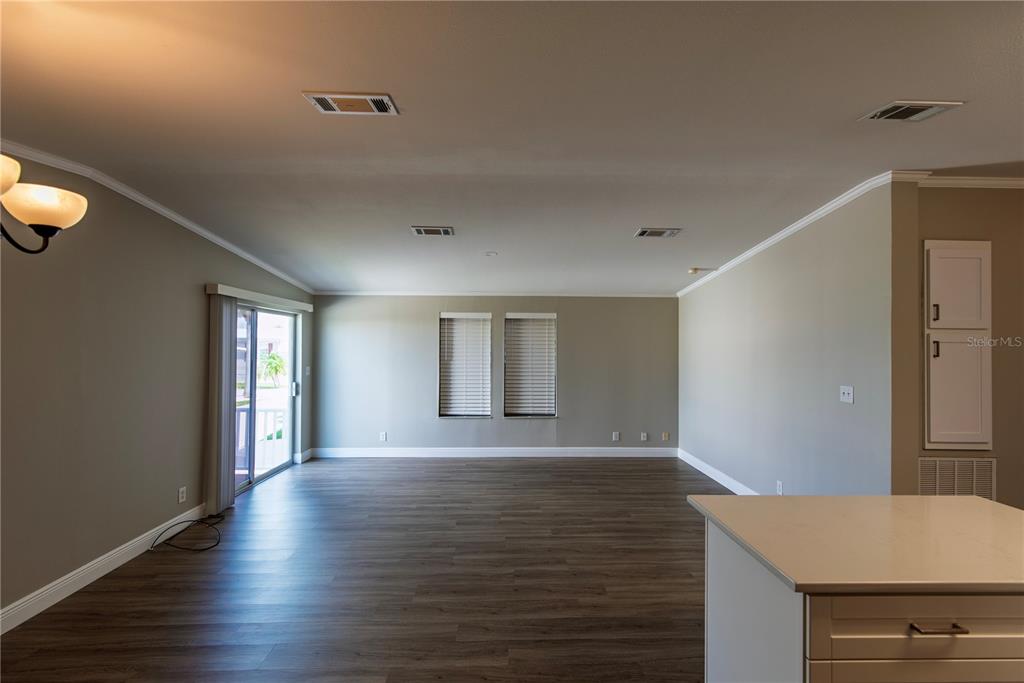 An open living area features wood-look flooring, neutral walls, two windows, and a sliding door — 25 COPENHAGEN AVENUE, PUNTA GORDA, FL