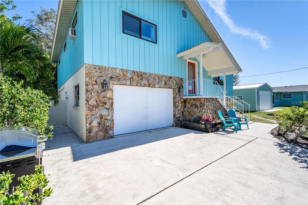A two-story house with blue vertical siding, a stone-faced lower level, and a white garage — 521 PAMETO ROAD, NOKOMIS, FL