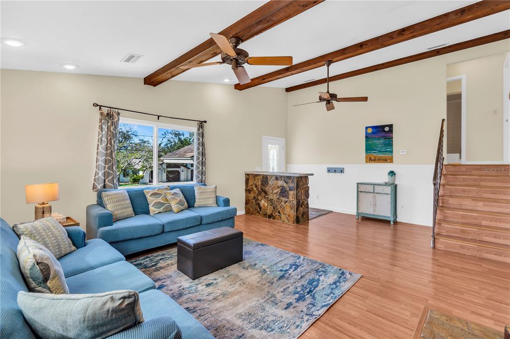 A living room features blue sofas, a stone bar, wood-beam ceilings, and wood-look flooring — 521 PAMETO ROAD, NOKOMIS, FL