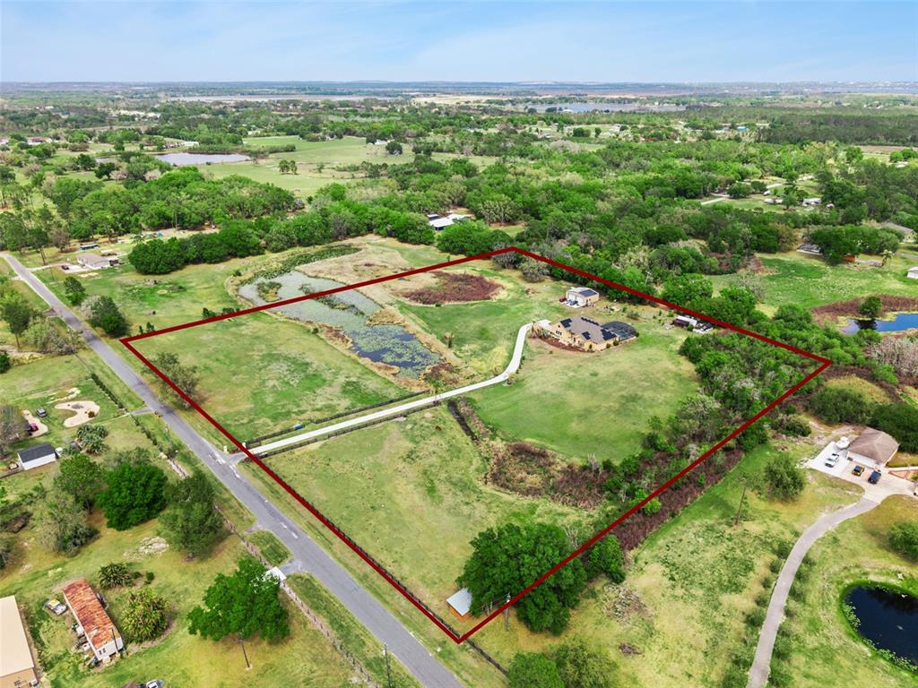 An aerial view shows a house with a pond and driveway on a large lot — 7139 GROVELAND FARMS ROAD, GROVELAND, FL