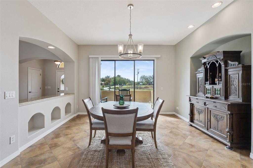 A dining room features a round wooden table, chairs, a hutch, and sliding glass doors — 7139 GROVELAND FARMS ROAD, GROVELAND, FL