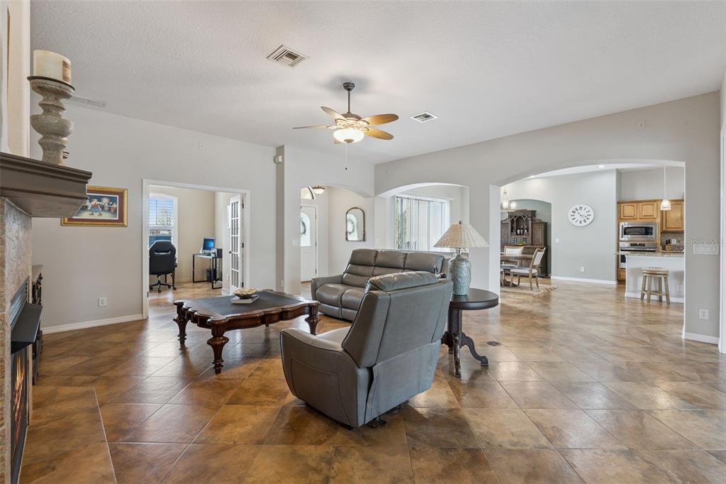 A living room with tile floors, a fireplace, and an open floor plan layout — 7139 GROVELAND FARMS ROAD, GROVELAND, FL
