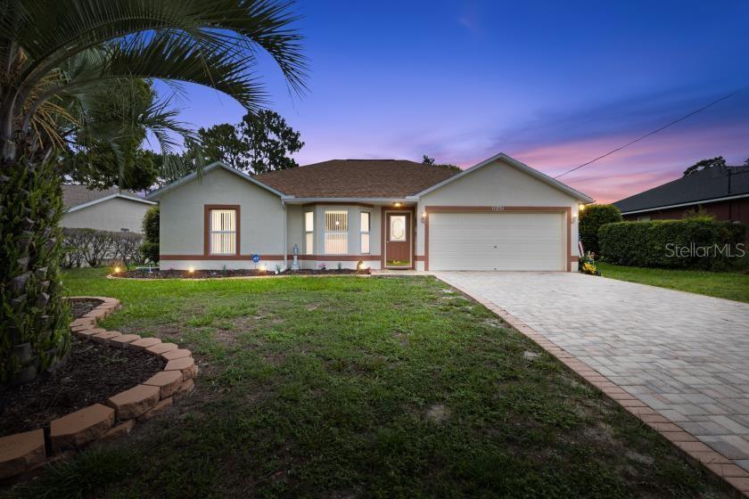 A single-story house with a paved driveway, tan stucco exterior, and a two-car garage — 11251 PICKFORD STREET, SPRING HILL, FL
