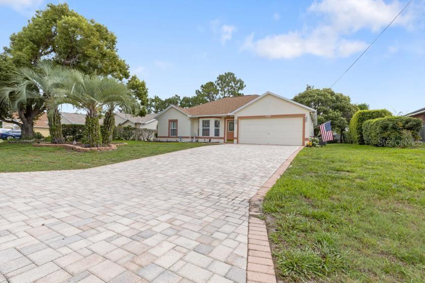 A single-story house with a paved driveway, a two-car garage, and palm trees in front — 11251 PICKFORD STREET, SPRING HILL, FL