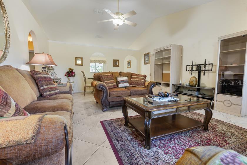 A living room features tile flooring, a vaulted ceiling, a ceiling fan, and brown furniture — 11251 PICKFORD STREET, SPRING HILL, FL