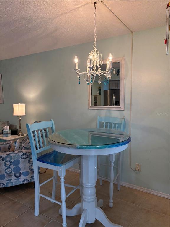 A dining area features a round table with two chairs, a chandelier, and a wall mirror — 14531 WALSINGHAM ROAD UNIT 224, LARGO, FL