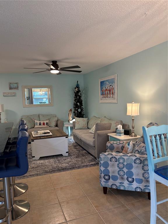 A living room features light blue walls, a gray sofa, and a patterned armchair — 14531 WALSINGHAM ROAD UNIT 224, LARGO, FL