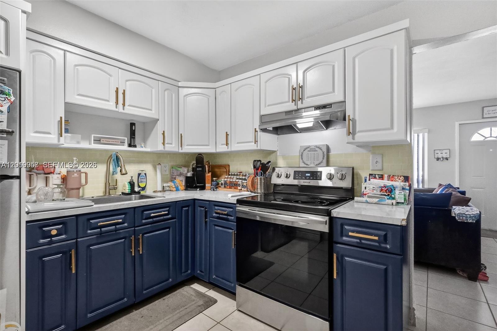 A kitchen features white upper cabinets, blue lower cabinets, and stainless steel appliances — 6791 Scott St, Hollywood FL 33024, HOLLYWOOD, FL