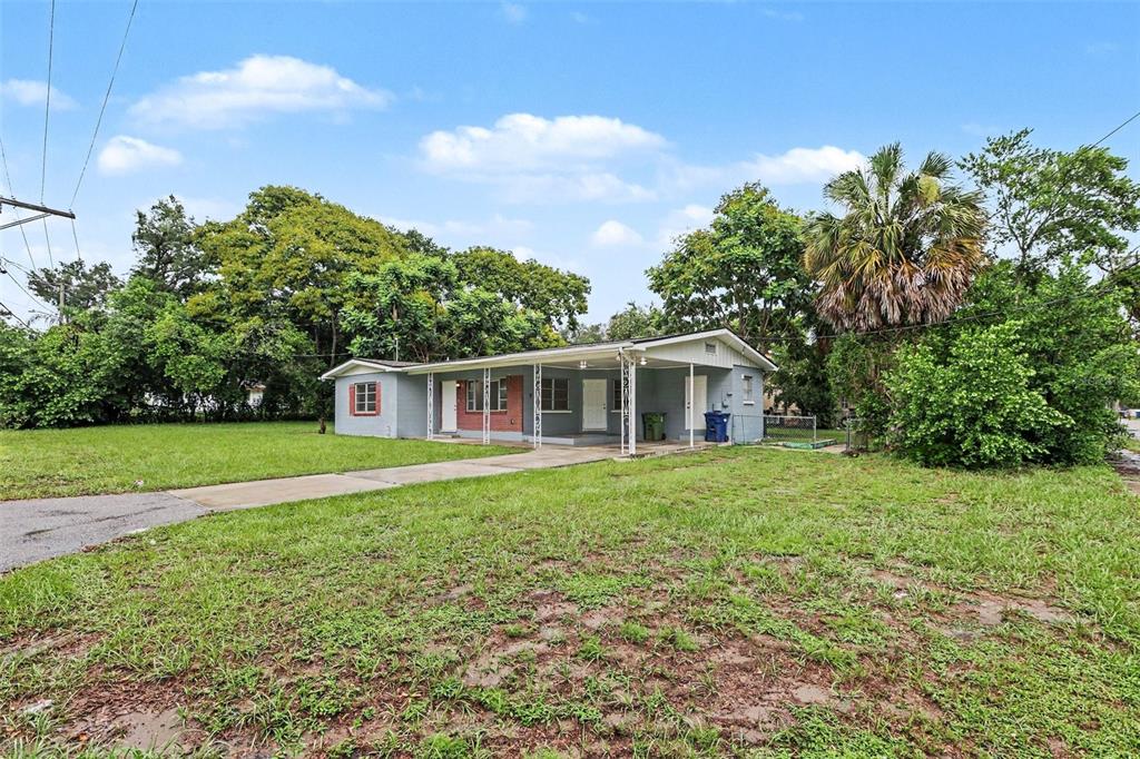 A single-story gray house with a carport sits on a large, grassy lot — 8101 N 17TH STREET, TAMPA, FL
