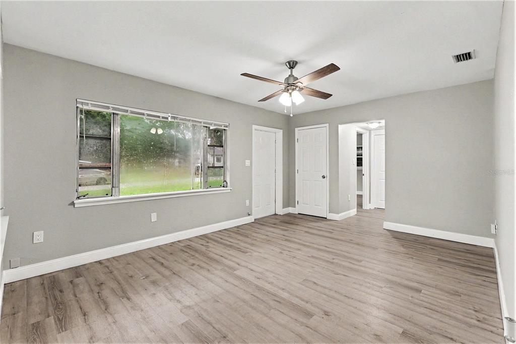 A room with gray walls, wood-look flooring, a ceiling fan, and two interior doors — 8101 N 17TH STREET, TAMPA, FL