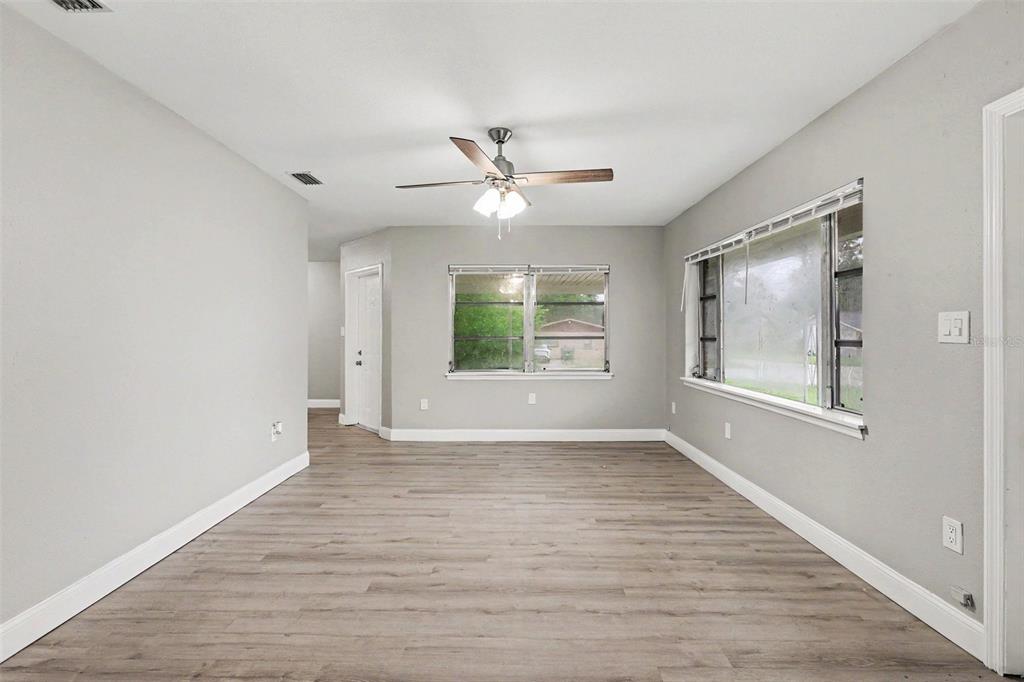 An empty room features light gray walls, wood-look flooring, a ceiling fan, and two windows — 8101 N 17TH STREET, TAMPA, FL