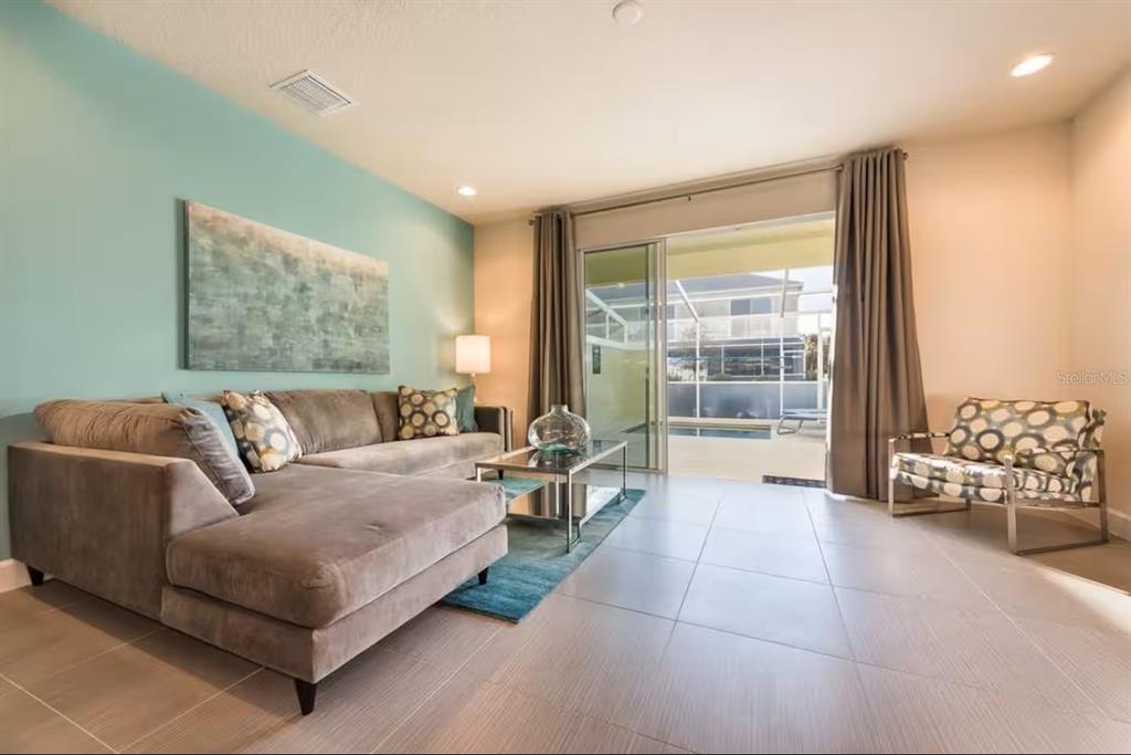 A living room features a grey sectional sofa, a glass coffee table, and a pool view — 1425 RETREAT CIRCLE, CLERMONT, FL