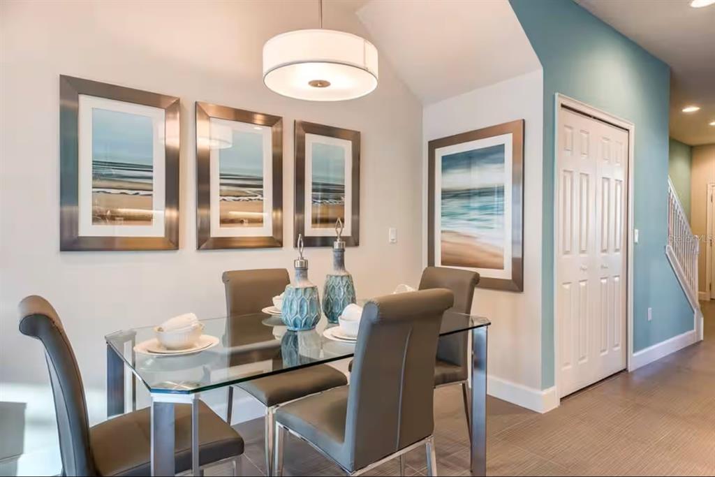 A dining room features a glass table, gray chairs, coastal wall art, and a pendant light — 1425 RETREAT CIRCLE, CLERMONT, FL