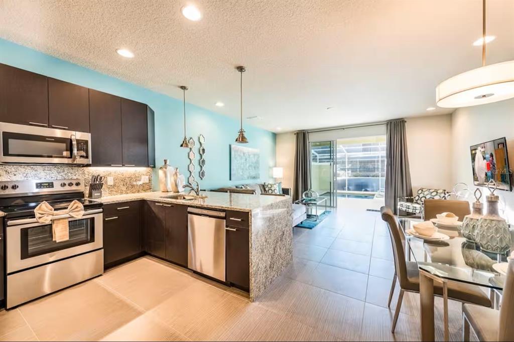 A kitchen with dark cabinets and granite countertops opens to a dining and living area — 1425 RETREAT CIRCLE, CLERMONT, FL